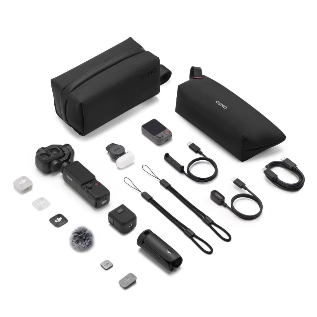 A DJI drone accessories kit laid out on a white background, including two black soft carrying cases, a drone body, batteries, cables, a microphone wind muffler, small accessories, and a remote.