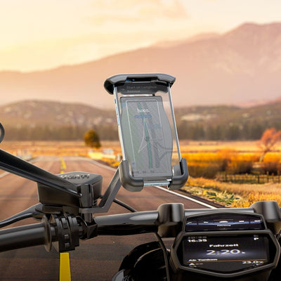 Motorcycle handlebar with phone mount and digital display against a scenic road backdrop
