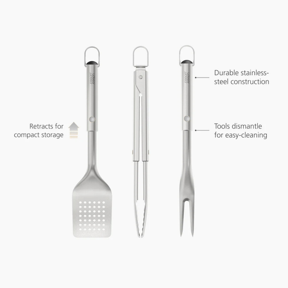 Joseph Joseph 3-piece stainless-steel BBQ turner, tongs, and fork set on a wooden surface, ready for grilling.
