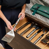 Joseph Joseph GrillOut 4-piece stainless-steel BBQ utensil set displayed with storage case on a wooden table.