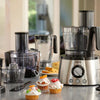 Kitchen appliances including a food processor and blenders on a counter with cupcakes.