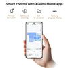A hand holds a smartphone showing a Xiaomi Home app floor plan and cleaning control interface, with feature icons and text above reading Remote activation, Scheduled cleaning, Set no-go zones, and Cleaning progress display.